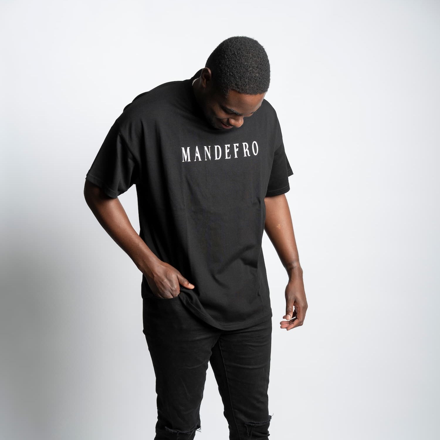 Man wearing a black oversized t-shirt with 'MANDEFRO' text on a white background