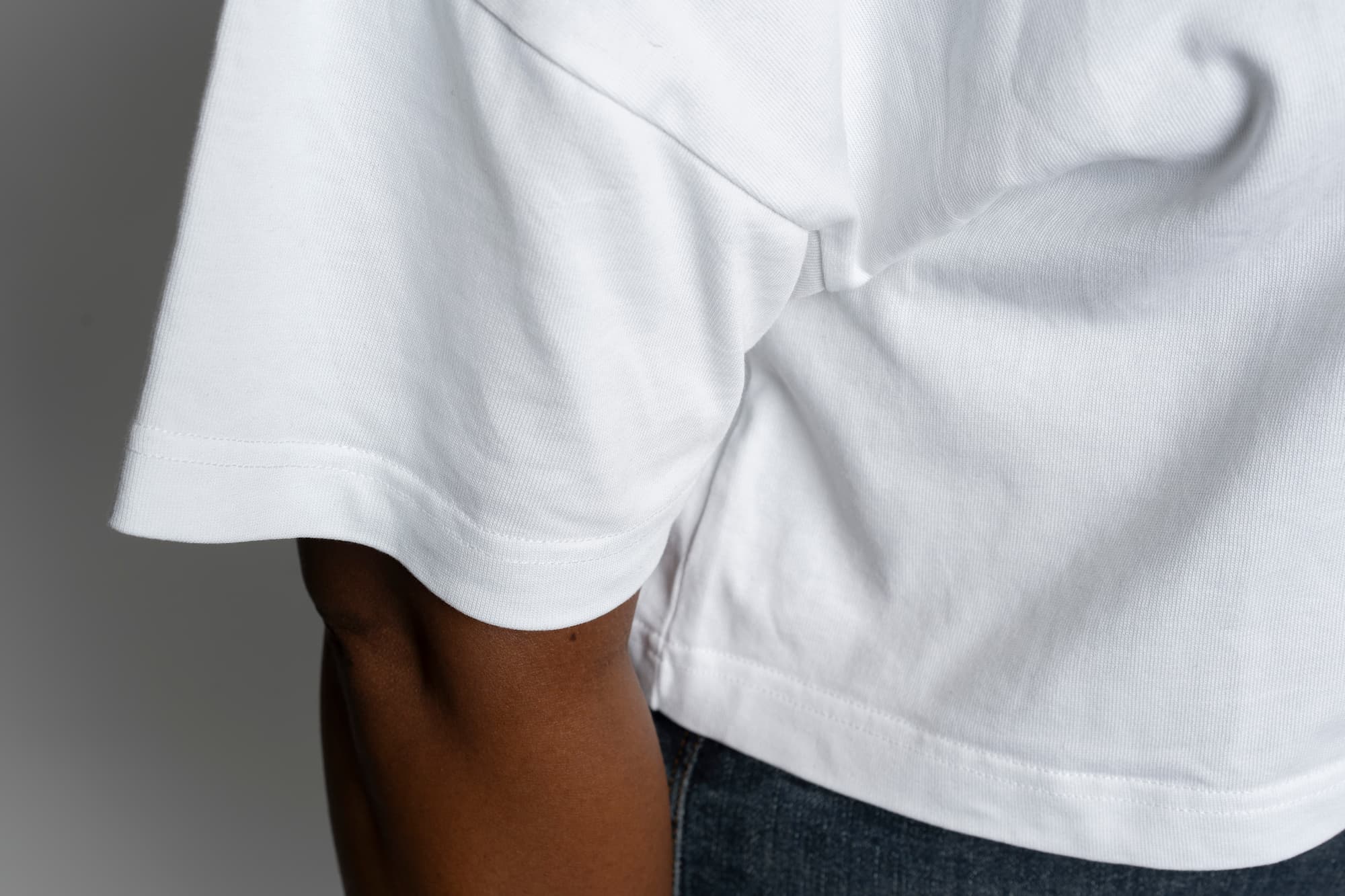 Close-up of a person wearing a white t-shirt with a gray background