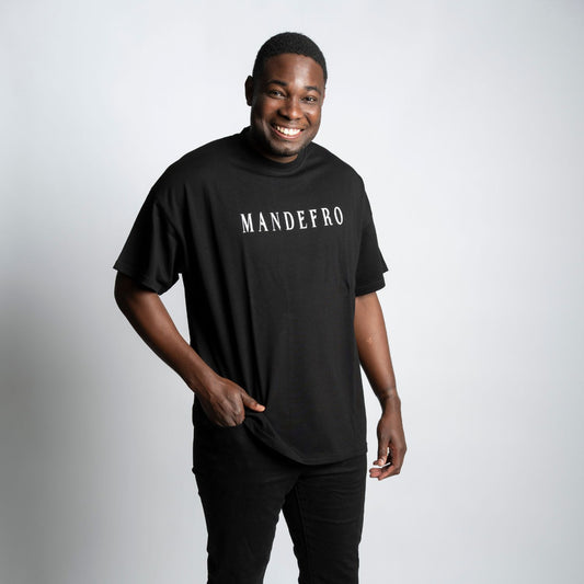 Man wearing a black oversized t-shirt with 'MANDEFRO' text on a white background